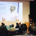 A woman giving a conference speech to a room full of people