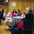 A woman asking a question to speakers at a conference