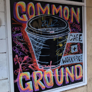 A chalk board sign with a coffee cup illustration and Common Ground typography