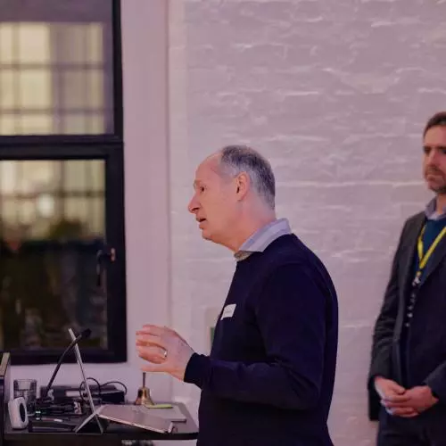 A speaker at a podium addressing the audience at a startup event