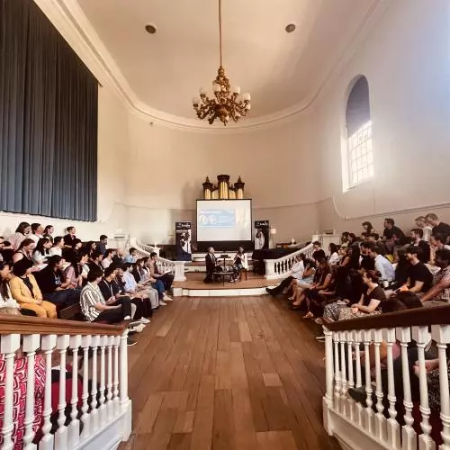 two speakers sat in front of a audience giving a talk