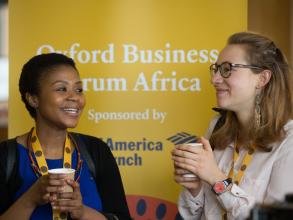 Two women talking and standing in front of a Oxford Business Forum Africa banner