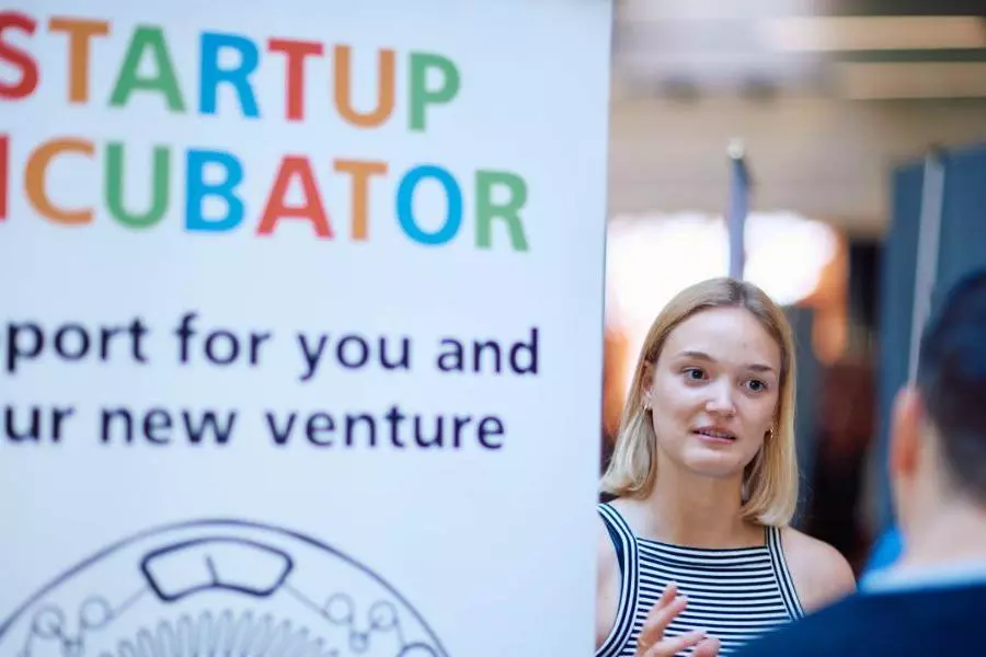 A women talking to somebody stood next to a Startup Incubator pull up banner